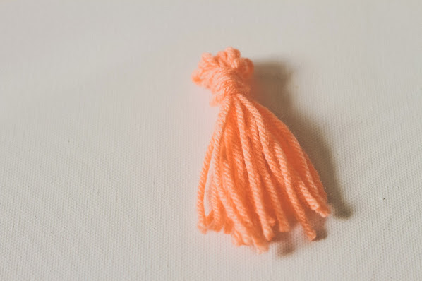 Wrap your gifts in an unconventional style with a gold chain and yarn tassel!